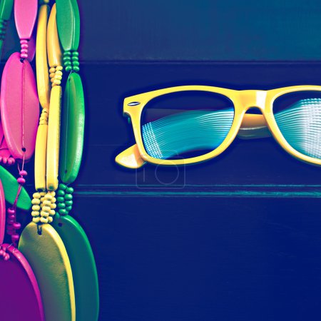 Glasses and brightly colored beads on black grungy background