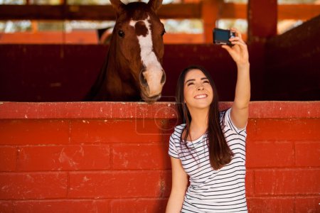 Brunette taking a selfie with his horse in the stables