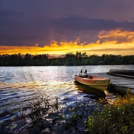 Boat docked on lake at sunset