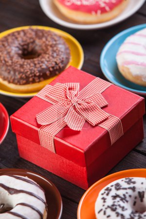 Donuts and gift on wooden table.