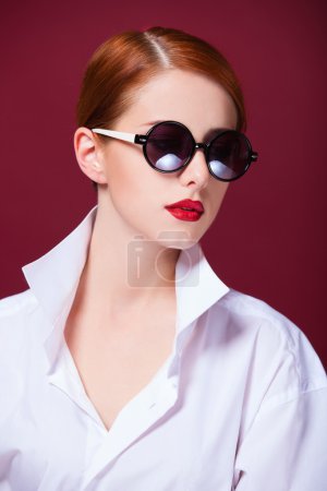 Redhead in sunglasses on red background