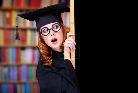 Graduating student girl in an academic gown near blackboard