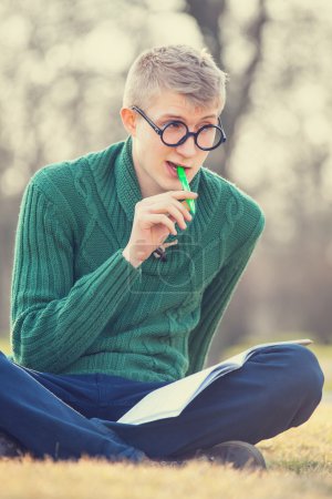Funny student with pen on a grass