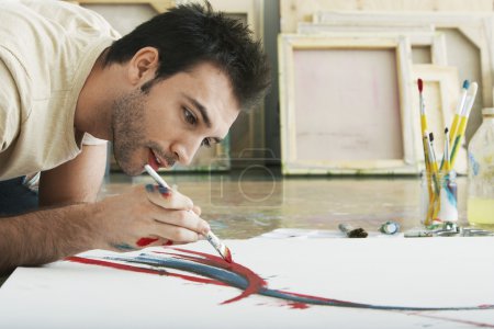 Man painting on canvas on studio floor