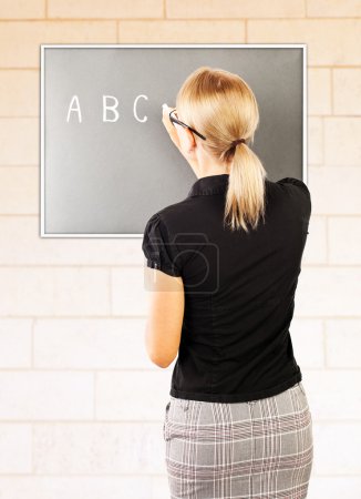Young teacher write on blackboard