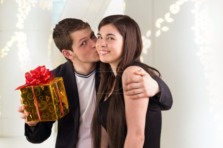 Man holding gift for woman and kissing her