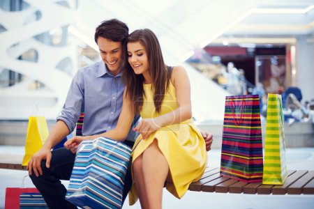 Happy couple peeking into shopping bag