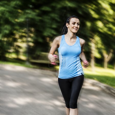 Active woman jogging with dumbbells