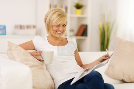 Blonde woman relaxing at home with coffe and newspaper