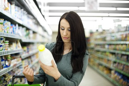 Woman choosing bottle of milk at supermarket