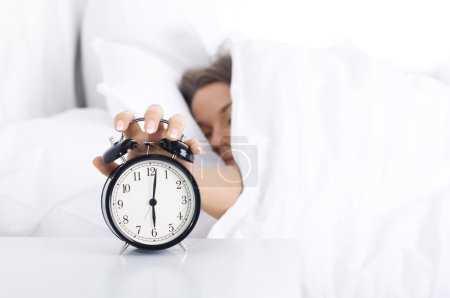 Woman turning off the alarm clock