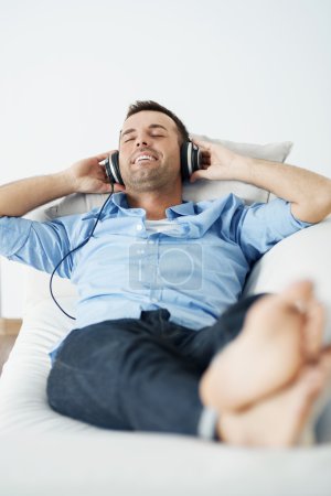 Man wearing headphones lying on the sofa
