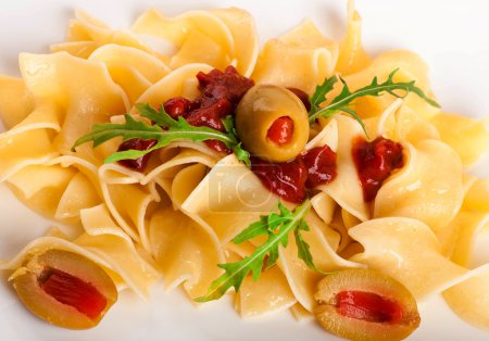 Pasta with tomato and arugula on the wooden table