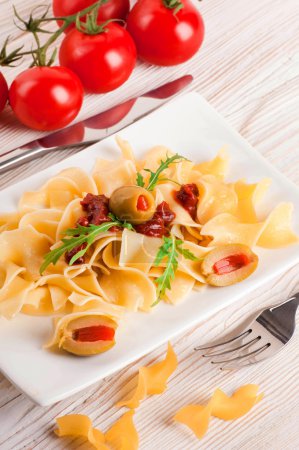 Pasta with tomato and arugula on the wooden table