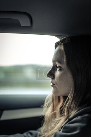 Sad woman into a car