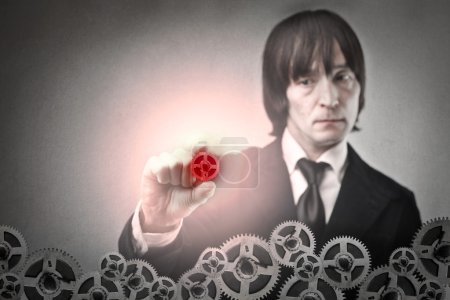 Businessman holding a red gearwheel