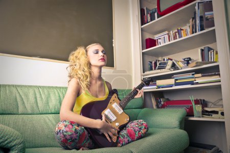 Young woman playing the eletric guitar