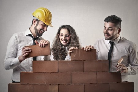 Businessmen and a business woman building a wall