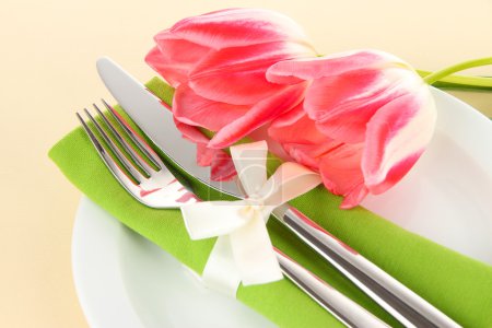 Festive dining table setting with tulips on beige background