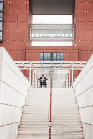 Businessman on wheelchair in front of stairs