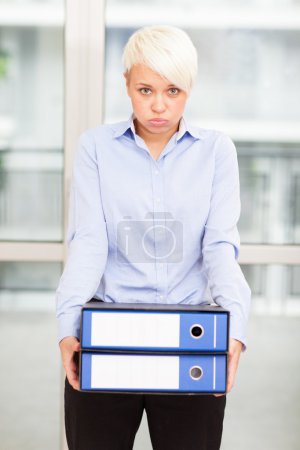 Tired woman with heavy binders in her hands