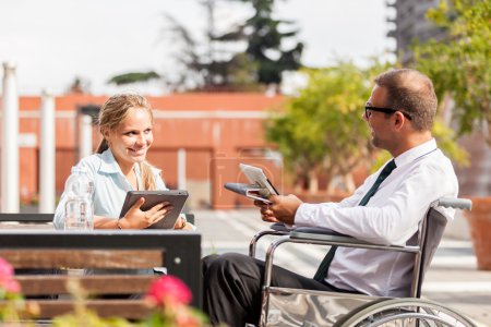 Businessman on wheelchair talks to his colleague