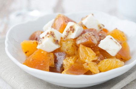 Salad with persimmon, mandarin oranges and goat cheese closeup