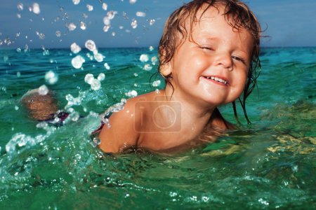 Happy kid splashing in the sea