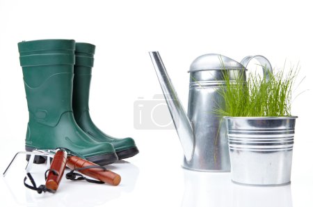Garden tools and watering can with grass on white