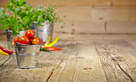 Tomatoes, chives and chili peppers on a wooden table top 