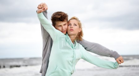 Couple running on beach holding hands smiling