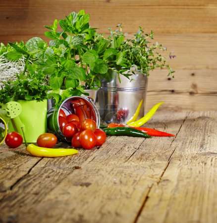 Tomatoes, chives and chili peppers on a wooden table top 
