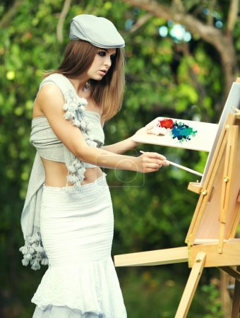 Fashion woman is painting. Open air session.