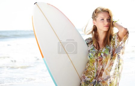 Beautiful young woman at the beach with surfboard