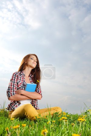 Beautiful girl lies on meadow and reads the boo