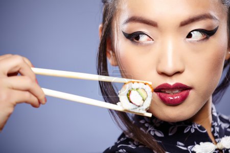 Sushi woman holding sushi with chopsticks looking at the camera