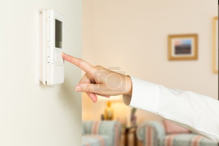Caucasian lady pressing modern thermostat