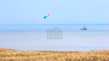 North Sea Coast With Crabber Boat And Wind Kite On The Sky
