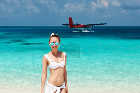 Woman at beach. Seaplane at background.