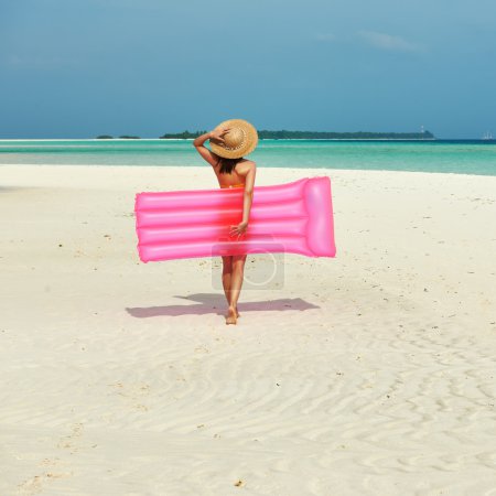 Woman with pink inflatable raft at the beach