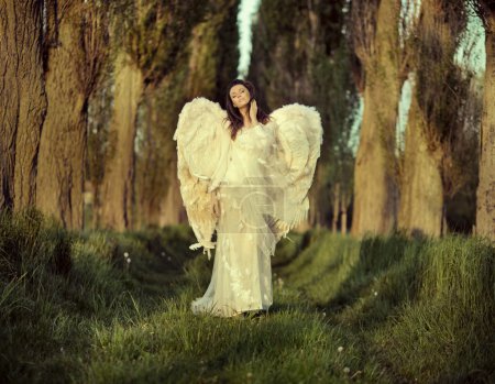 Wonderful female angel walking across the forest