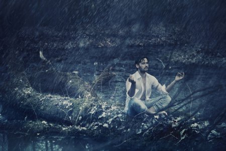 Art photo of handsome man meditating in the rain