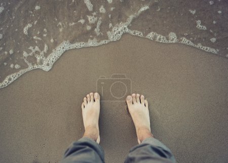 Picture of male bare foot near the sea water