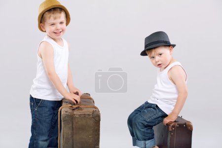 Two brothers posing with huge suitcases