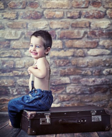 Small kid playing on the suitcase