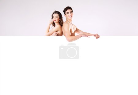 Happy young couple naked behind the board