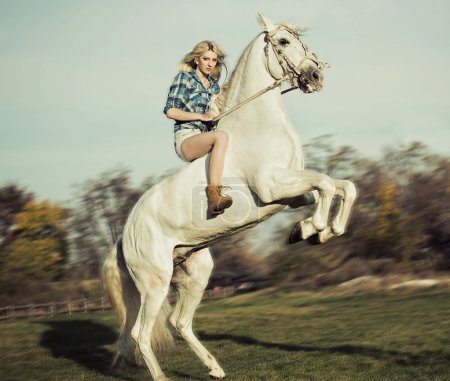 Serious blonde woman riding the horse