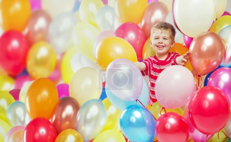 Laughing boy playing among the baloons