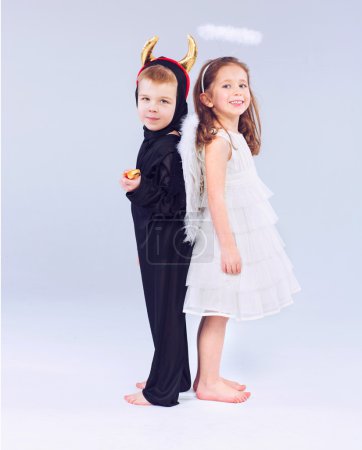 Cute little children as devil and angel