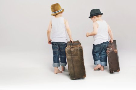 Two cute brothers leaving with their suitcases